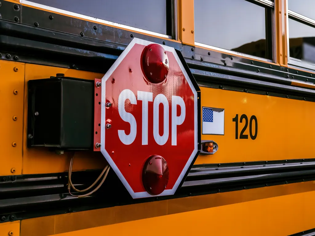 Close-up of the red STOP arm folded against the side of a yellow school bus